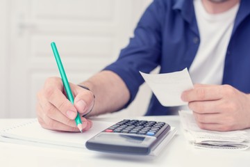 Male holding bills in her hands, man calculating family budget, calculator on the desktop, men's hands, cropped image, close up, toned