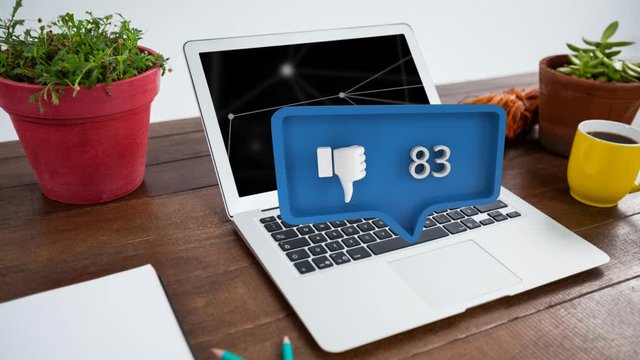 Thumbs down symbol and increasing numbers over laptop and plants on table
