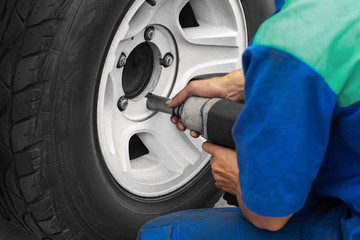 close up auto mechanic changing car wheel with tool machine , home services concept