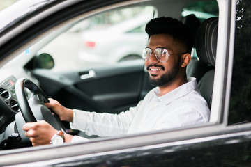 Portrait of an handsome smiling asian man driving his car with white shirt on the road