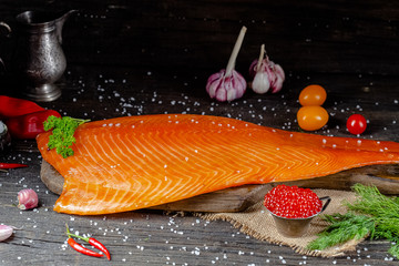 a large piece of red fish fillet with vegetables and spices and fresh herbs, stand and lie, from...