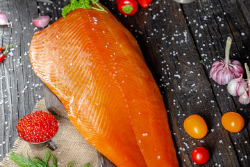 a large piece of red fish fillet with vegetables and spices and fresh herbs, stand and lie, from...