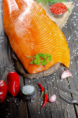a large piece of red fish fillet with vegetables and spices and fresh herbs, stand and lie, from...