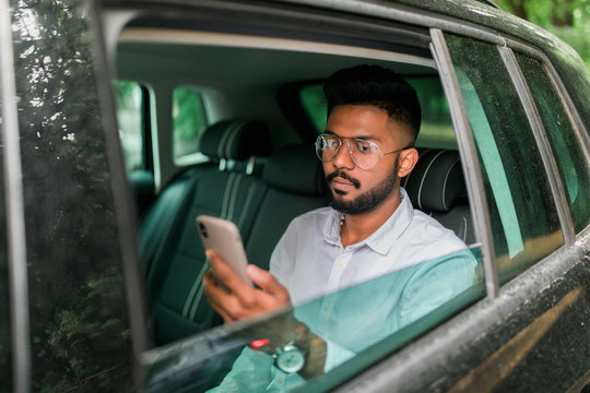 Casual Young Indian Business Man Use Smartphone In The Car Sitting In The Back