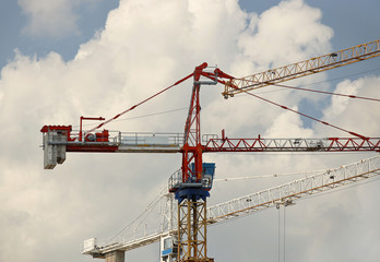 Tower cranes work during the construction of a multi-story building. New apartments for residents and premises for offices. Risky work at height. Lifting heavy building materials. City development
