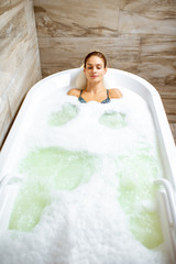 Beautiful woman relaxing in the bathtub having a hydromassage therapy in the SPA. View from above