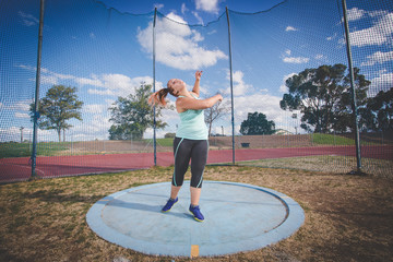 Wide angle action photo of a female discus athlete throwing a discus