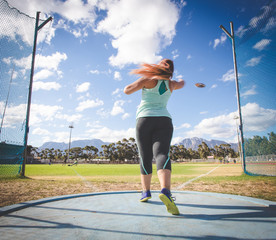 Wide angle action photo of a female discus athlete throwing a discus