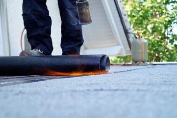 Flat roof installation with propane blowtorch during construction works with roofing felt. Heating...