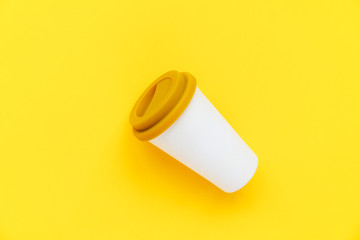 White bamboo coffee to go cup with a yellow rubber lid on a yellow background. Diagonal isometric view. Flat lay