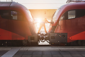 Technician inspect and connect coupling both the train locomotive together at railway station