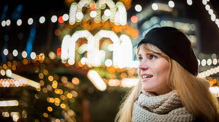 Happy smiling girl at Christmas market, illuminated bokeh background