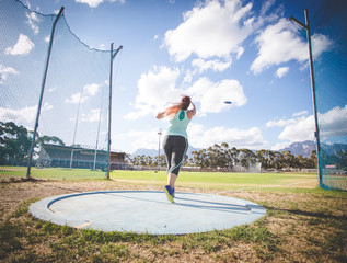 Wide angle action photo of a female discus athlete throwing a discus