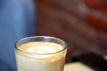  Aromatic coffee with a pattern in a glass cup on a brick wall background.