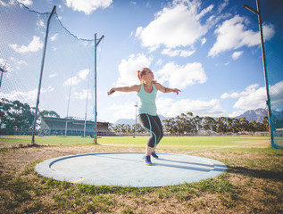 Wide angle action photo of a female discus athlete throwing a discus