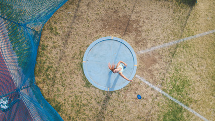 Wide angle action photo of a female discus athlete throwing a discus