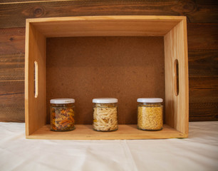 glass jars filled with italian pasta with wooden background