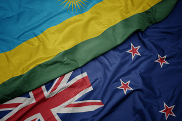waving colorful flag of new zealand and national flag of rwanda.