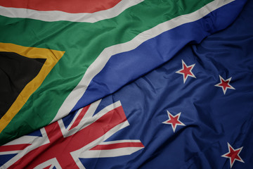 waving colorful flag of new zealand and national flag of south africa.