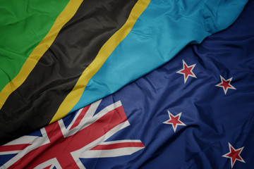 waving colorful flag of new zealand and national flag of tanzania.