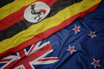 waving colorful flag of new zealand and national flag of uganda.