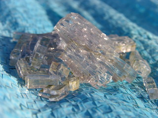 The squares are glass (broken tempered glass) and the squares are blue (plastic).  Contrasts - some hard, sharp, colorless, and other plastic, flexible and colored. shallow focus. close up.