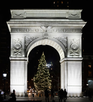 New York, New York, USA - December 18, 2015: The Washington Square Arch and Christmas tree as seen at night. Silhouettes of people can be seen taking photos and walking.