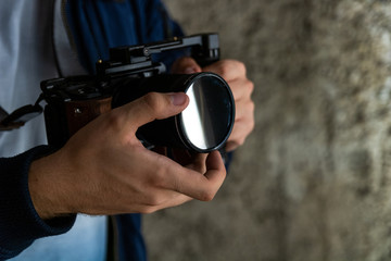 Young man sliding his variable ND Filter on camera. finding a good setting for recording video.