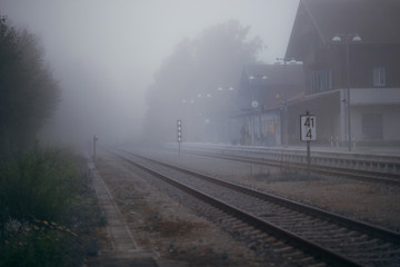 Naklejka na ściany i meble Railway station in the fog, the railway tracks are shrouded in fog, foggy morning