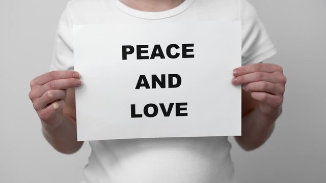 Woman In White T-Shirt Holding A sign Peace and Love. Medium shot.