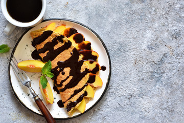 Classic breakfast - crepes with caramel peaches and chocolate sauce. Breakfast and a cup of coffee.