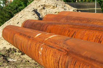 Several metal pipes lying on the street for laying sewage.