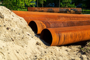 Several metal pipes lying on the street for laying sewage.