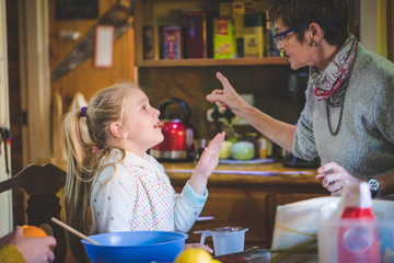 Close up lifestyle image of a young girl baking cake with her grandmother