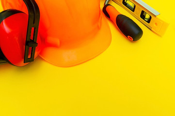 Protective equipment and tools in a bag for the builder on a yellow background.