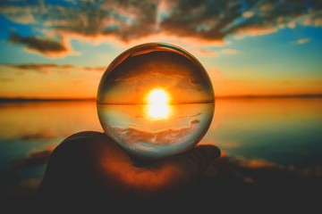 Creative crystal lens ball photography of the sunset with clouds blurred in the background