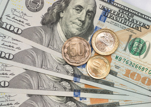 Chilean peso coin on top of dollar bills