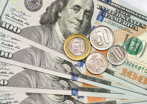 Venezuelan coin on top of dollar bills