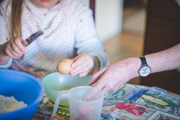 Close up lifestyle image of a young girl baking cake with her grandmother