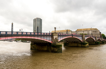 Fototapeta premium Arches of Lambeth bridge and brown waters of river Thames flowing through, London, England