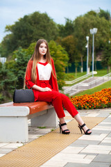 Young beautiful woman in red suit on the summer street