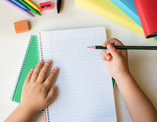 school desk background with children hands holding a pencil