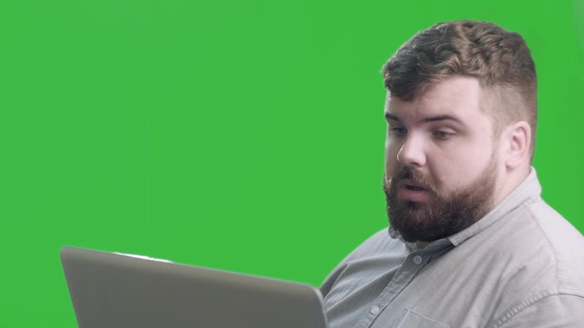 Surprised business man talking laptop at green scren background. Portrait of smiling professional have conversation on laptop. Chroma key. 4k