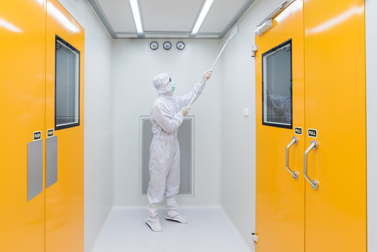 A Scientist In Sterile Coverall Gown Using Cleaning Tool For Cleaning Laboratory. Cleanroom Facility.