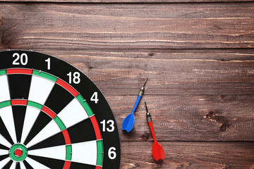 Dartboard with darts on brown wooden table