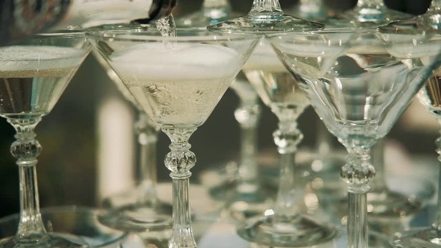 Waiter pours champagne on glasses on wedding outdoors. close up.