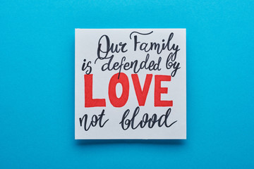 top view of card with our family is defended by love not blood lettering on blue background