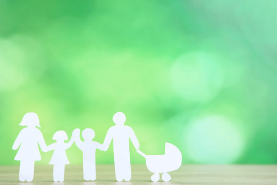 Paper family figures with stroller on green background