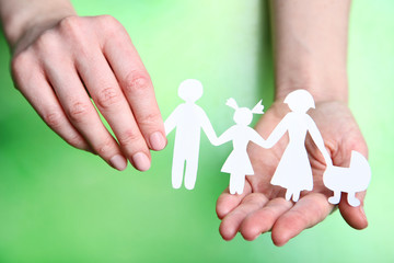 Family figures in female hands on green background