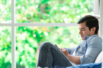 Fototapeta premium Man using phone on couch. White man, relax mood.